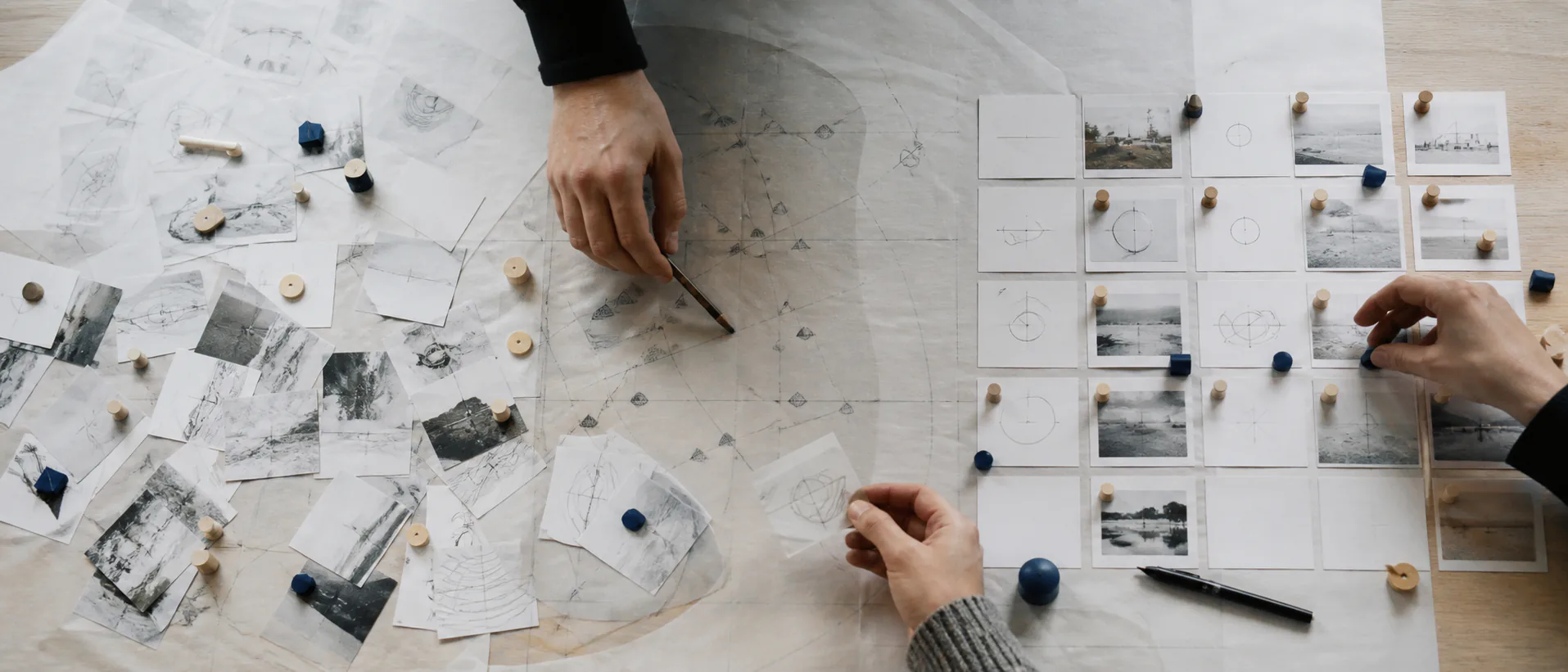 Hands sort unlabelled research images and tokens from a scattered field into an ordered grid on a project table.