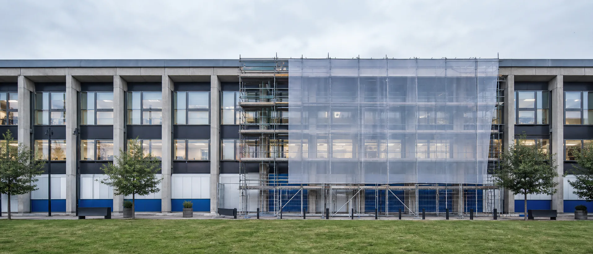 One bay of a modular civic building is carefully scaffolded while the surrounding bays remain in use.